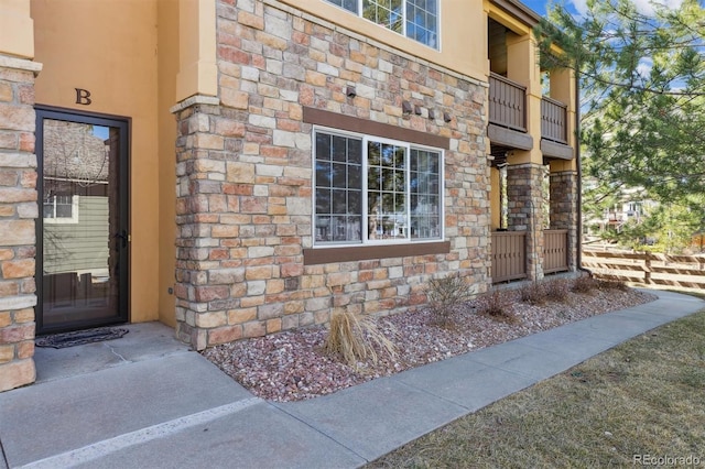 property entrance with stone siding and stucco siding