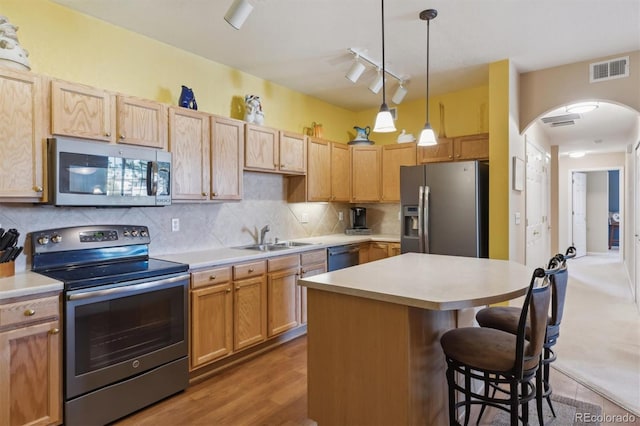 kitchen with stainless steel appliances, visible vents, decorative backsplash, a sink, and a kitchen bar