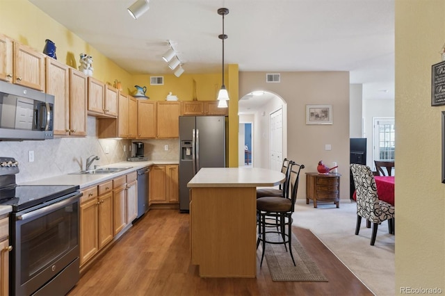 kitchen with arched walkways, visible vents, a center island, stainless steel appliances, and a sink