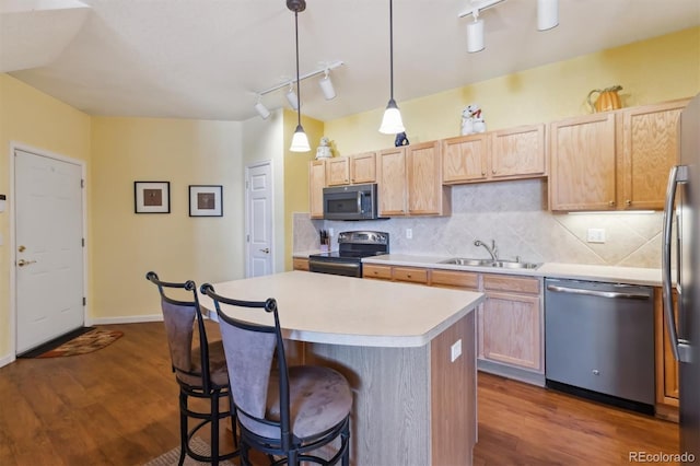 kitchen featuring stainless steel appliances, dark wood finished floors, a sink, and a kitchen bar