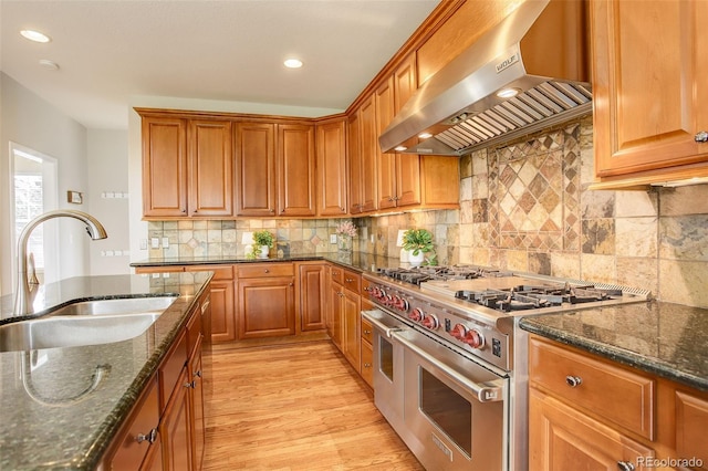 23427 Song Bird Hills Pl, Parker, CO 80138 - kitchen with range with two ovens, extractor fan, a sink, dark stone counters, and recessed lighting