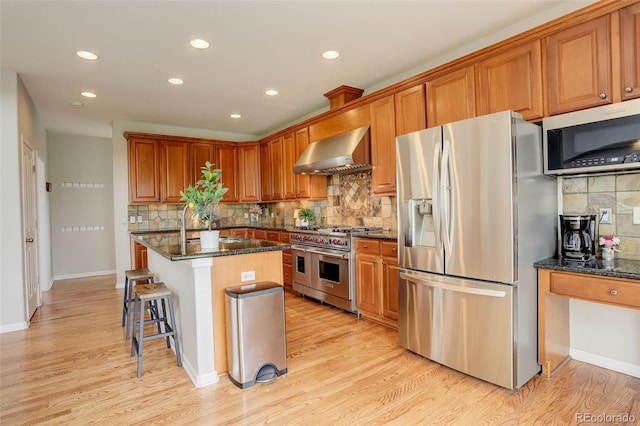 23427 Song Bird Hills Pl, Parker, CO 80138 - kitchen featuring stainless steel appliances, wall chimney exhaust hood, recessed lighting, backsplash, and dark stone counters