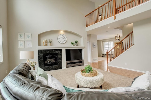 23427 Song Bird Hills Pl, Parker, CO 80138 - living area with a towering ceiling, stairs, a tile fireplace, baseboards, and wood finished floors