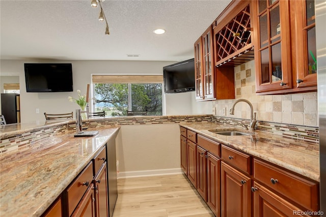 23427 Song Bird Hills Pl, Parker, CO 80138 - kitchen with a sink, light wood finished floors, light stone countertops, decorative backsplash, and brown cabinetry