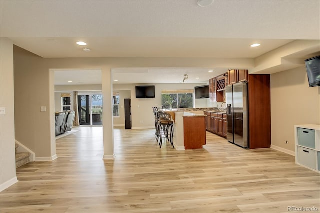 23427 Song Bird Hills Pl, Parker, CO 80138 - kitchen with stainless steel refrigerator with ice dispenser, a breakfast bar area, light wood-style flooring, baseboards, and recessed lighting