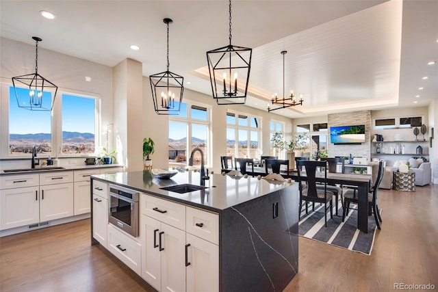 kitchen featuring a sink, a raised ceiling, dark countertops, and open floor plan