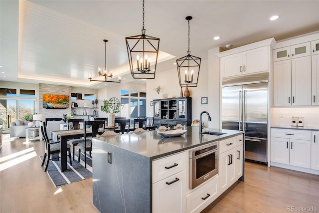 kitchen featuring a sink, stainless steel built in fridge, light wood-type flooring, and tasteful backsplash