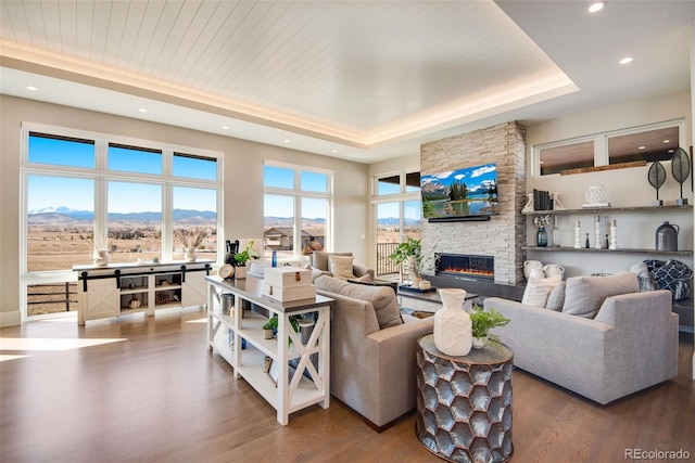 living area with a tray ceiling, wood ceiling, wood finished floors, and a fireplace