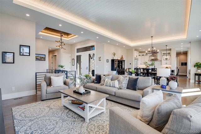 living area with baseboards, a chandelier, light wood-type flooring, a tray ceiling, and recessed lighting