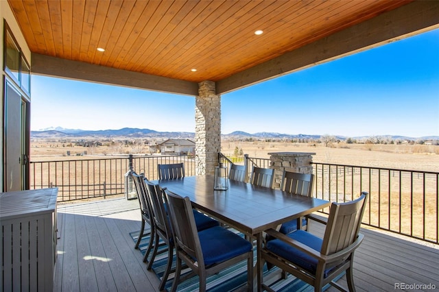 wooden terrace featuring outdoor dining space, a rural view, and a mountain view