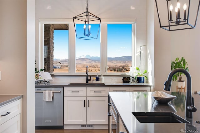 kitchen featuring dishwasher, dark countertops, white cabinetry, and a sink