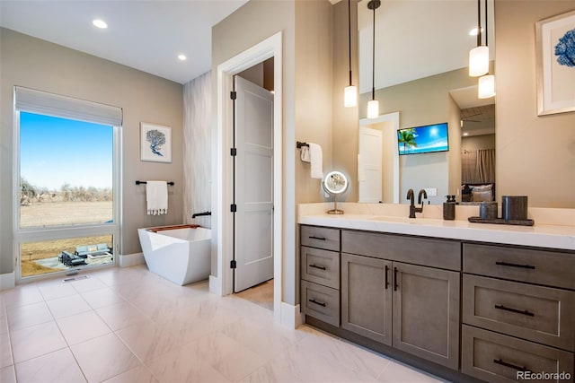 bathroom featuring vanity, recessed lighting, baseboards, and a freestanding bath