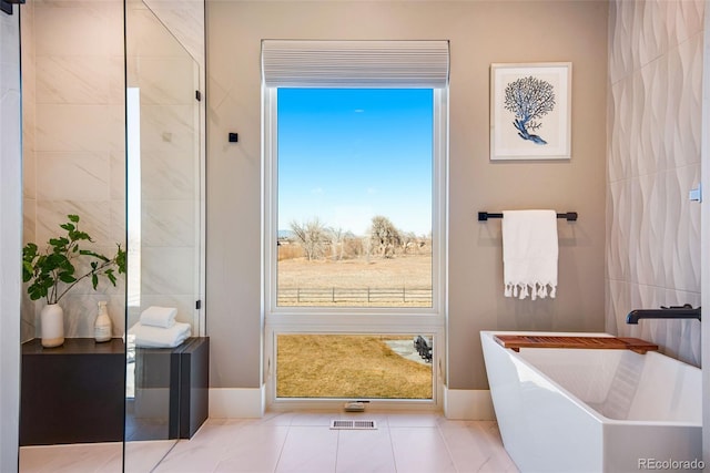 bathroom with tile patterned floors and a freestanding tub