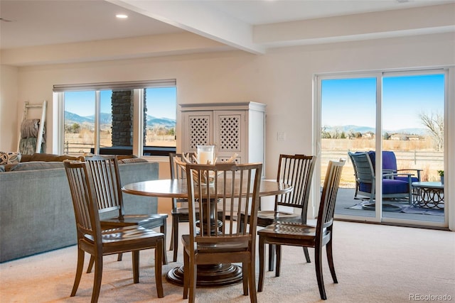 dining room with beam ceiling, recessed lighting, light colored carpet, and a mountain view