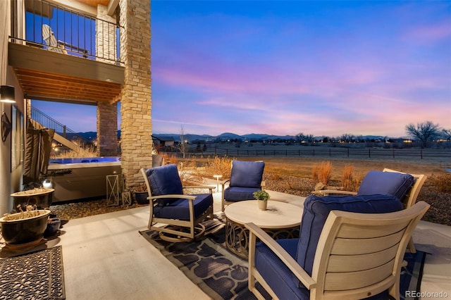 patio terrace at dusk featuring a balcony and fence