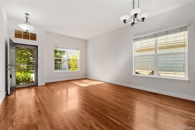 spare room with a notable chandelier and light hardwood / wood-style flooring