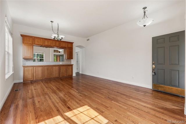 kitchen featuring tasteful backsplash, a notable chandelier, decorative light fixtures, and hardwood / wood-style flooring