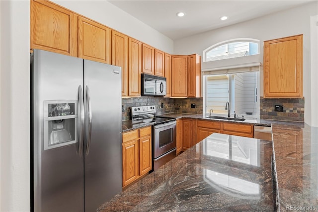 kitchen featuring appliances with stainless steel finishes, dark stone countertops, sink, and tasteful backsplash