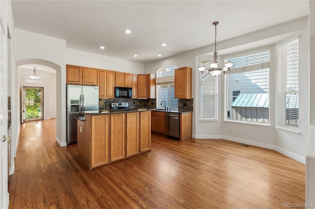 kitchen featuring pendant lighting, a kitchen island, dark wood-type flooring, sink, and stainless steel appliances