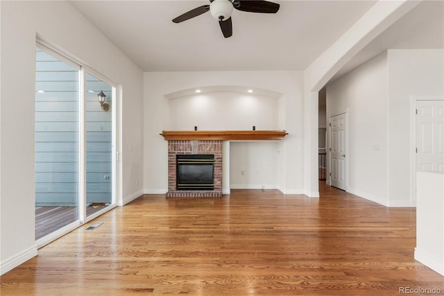 unfurnished living room featuring a fireplace, wood-type flooring, and ceiling fan