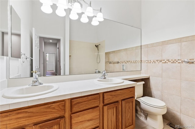 bathroom with a shower, toilet, tile patterned floors, tile walls, and vanity