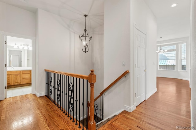 hall with a notable chandelier, sink, and hardwood / wood-style floors