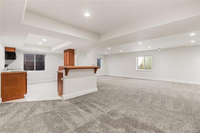 unfurnished living room with light carpet, sink, and a raised ceiling