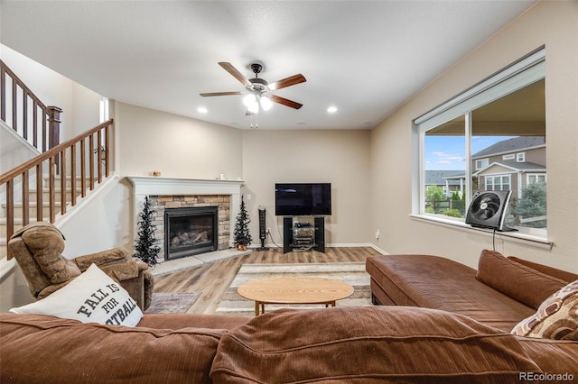 living room with a stone fireplace, hardwood / wood-style floors, and ceiling fan