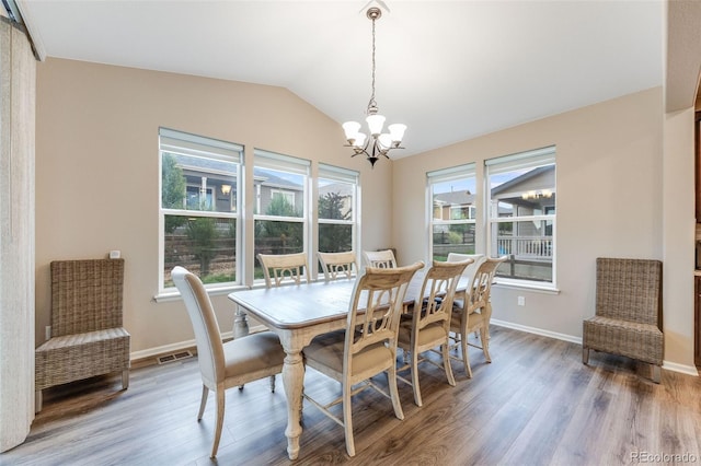 dining area with an inviting chandelier, lofted ceiling, and hardwood / wood-style floors