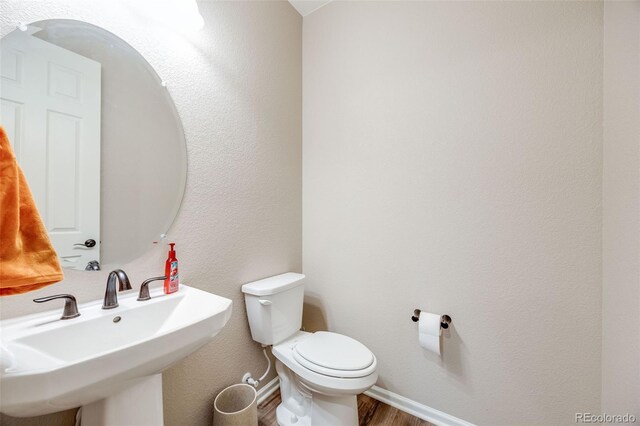 bathroom featuring wood-type flooring, toilet, and sink