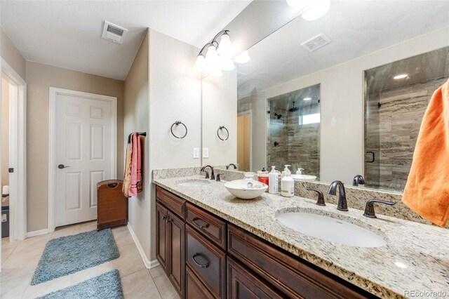 bathroom featuring tile patterned flooring, double sink vanity, and a shower with door