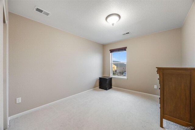 unfurnished room featuring light carpet and a textured ceiling