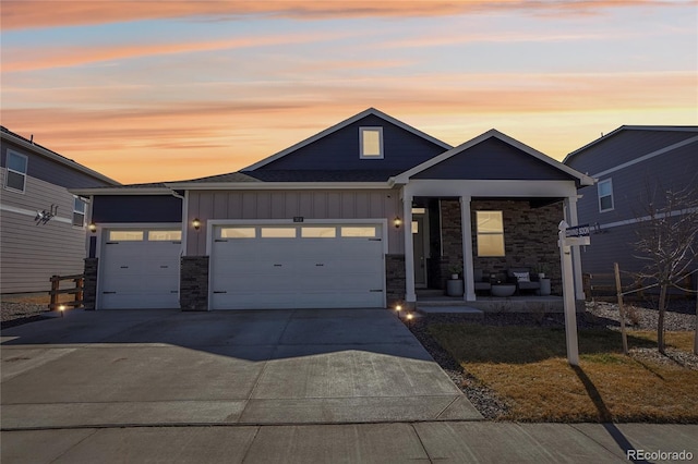 view of front of property with concrete driveway, a garage, board and batten siding, and stone siding