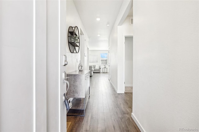 corridor featuring dark wood-type flooring and baseboards