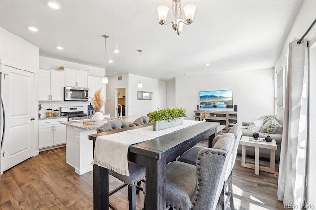 dining room with a chandelier, recessed lighting, and wood finished floors