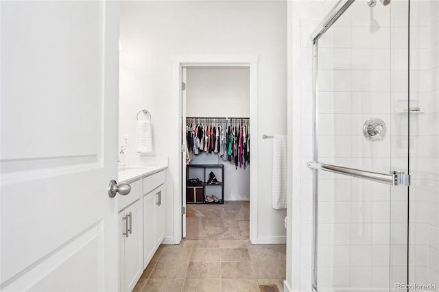 bathroom with vanity, a shower stall, a spacious closet, and tile patterned floors