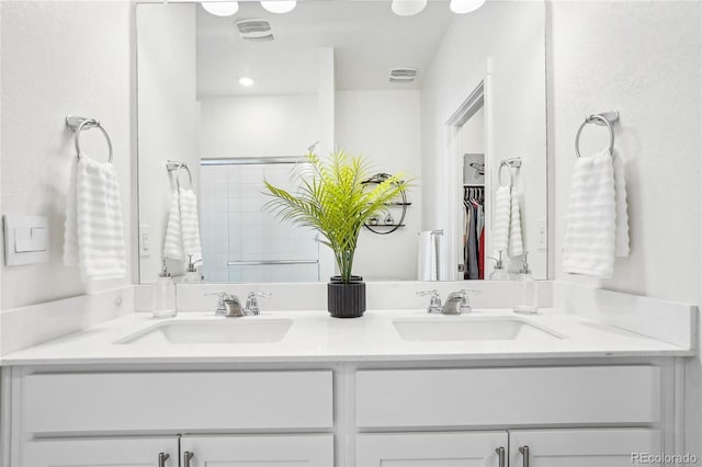 full bath featuring double vanity, visible vents, a walk in closet, and a sink