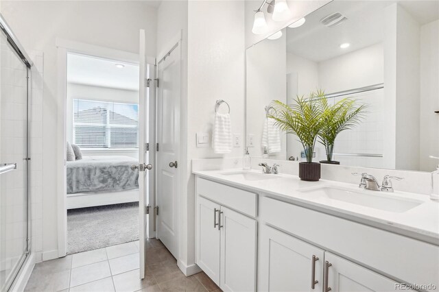 ensuite bathroom featuring a sink, a shower with door, and tile patterned flooring