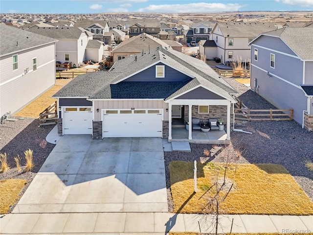 view of front of home featuring fence, driveway, an attached garage, a residential view, and board and batten siding