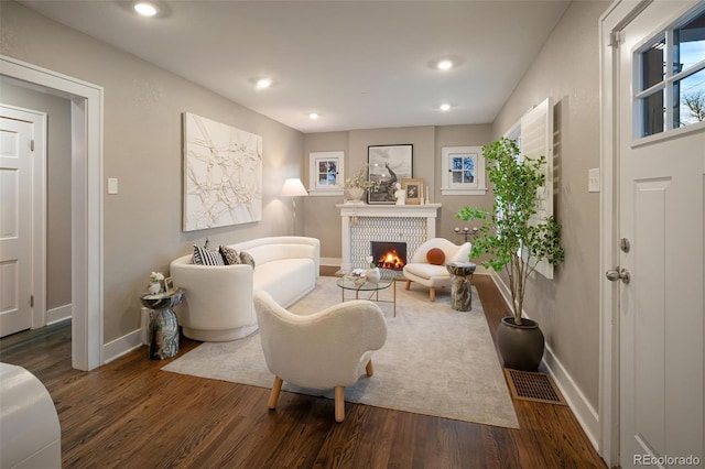 living area featuring a tiled fireplace, recessed lighting, baseboards, and wood finished floors