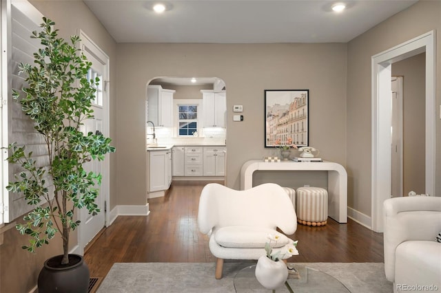 sitting room featuring arched walkways, recessed lighting, dark wood-type flooring, and baseboards