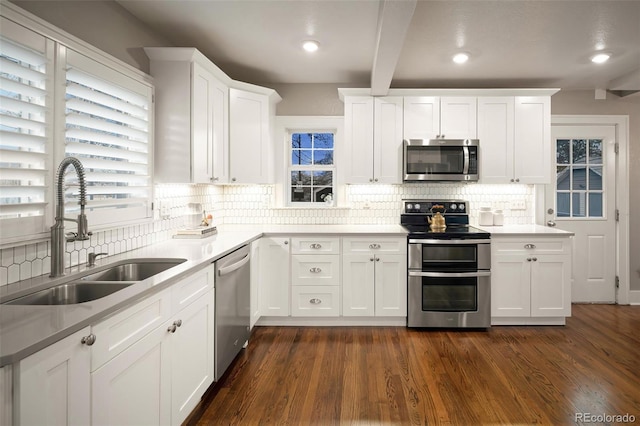 kitchen featuring a sink, backsplash, white cabinetry, appliances with stainless steel finishes, and dark wood-style flooring