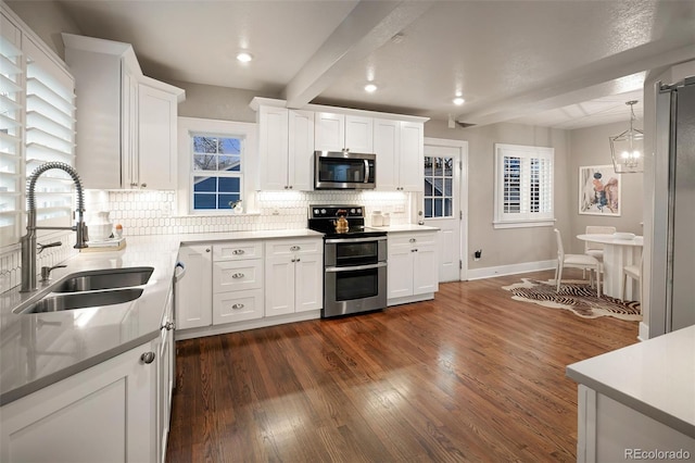 kitchen featuring beamed ceiling, a sink, backsplash, dark wood-style floors, and appliances with stainless steel finishes