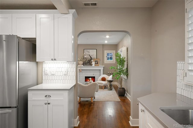 kitchen featuring visible vents, backsplash, a warm lit fireplace, and freestanding refrigerator