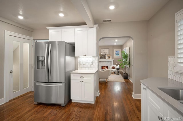 kitchen featuring tasteful backsplash, visible vents, stainless steel fridge with ice dispenser, white cabinets, and dark wood-style flooring