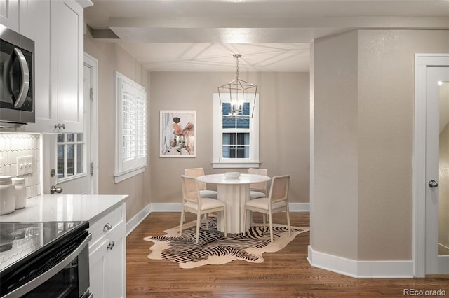 dining room featuring dark wood finished floors, a chandelier, and baseboards