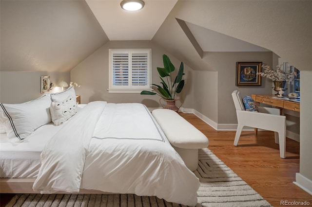 bedroom with vaulted ceiling, baseboards, and wood finished floors