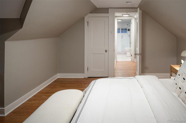 bedroom featuring baseboards, lofted ceiling, and wood finished floors