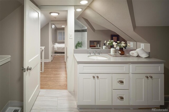 bathroom with lofted ceiling, wood finished floors, and vanity