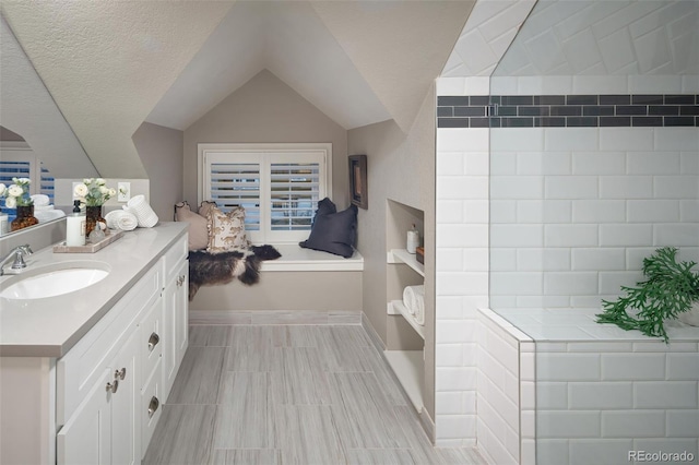 bathroom with vanity, lofted ceiling, and a textured ceiling